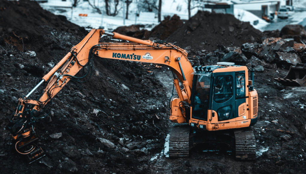 Oransje gravemaskin på anlegg