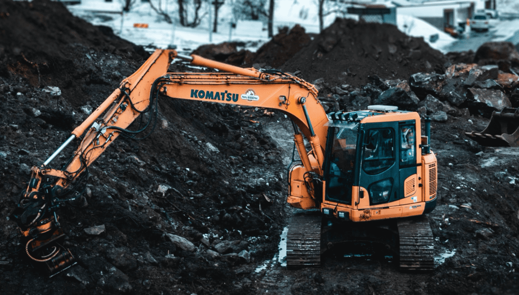 Oransje gravemaskin på anlegg